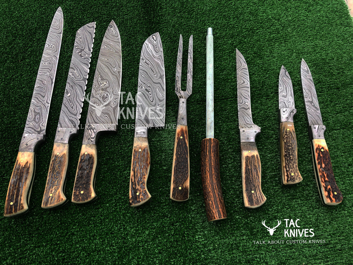 A set of eight custom knives and a carving fork with Damascus steel blades and natural antler handles, arranged on a green artificial turf background. The Tac Knives logo is visible on the image.