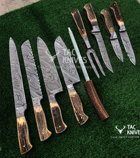 A set of custom knives and a carving fork with patterned Damascus steel blades and natural brown antler handles, arranged on a green textured background. The Tac Knives logo is visible on the blades and as a watermark.