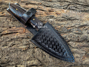 A black woven leather knife sheath with a dark wood-handled knife partially inserted, photographed on textured tree bark. The TAC KNIVES logo is visible on the sheath and as a watermark.