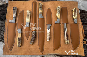 A set of custom knives with antler handles and steel blades, displayed in a brown leather roll-up case on a rustic wood background. The brand 'Tac Knives' is visible as watermarks and logos.